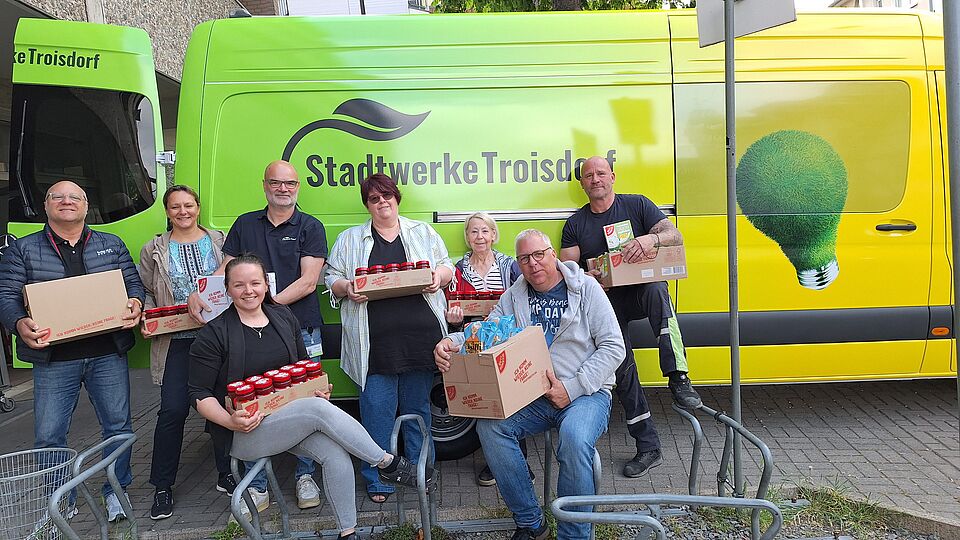 Tafel-Mitarbeiterin gemeinsam mit Stadtwerke-Betriebsrat vor dem Stadtwerke-Auto mit den Lebensmittelspenden im Arm
