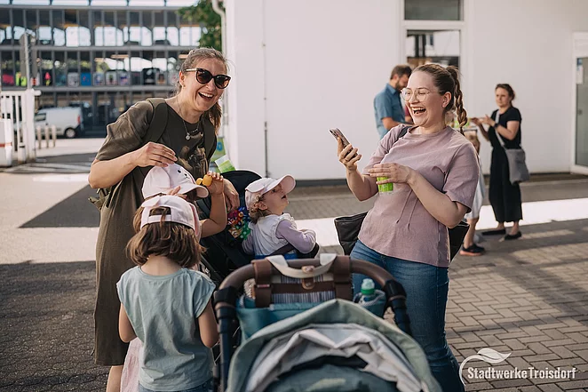 Zwei Frauen mit Kind und Kinderwagen freuen sich