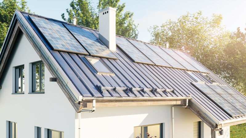 Haus mit Solaranlagen auf dem Dach Haus mit Solaranlagen auf dem Dach umgeben von einer grünen Landschaft