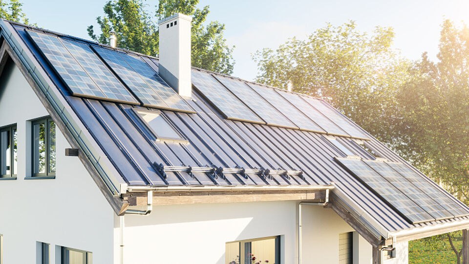 Haus mit Solaranlagen auf dem Dach umgeben von einer grünen Landschaft 