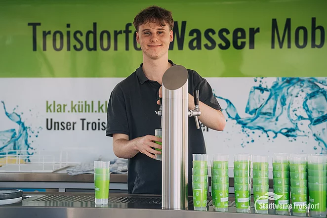 Junger Mann zapft Wasser im Wasserwagen