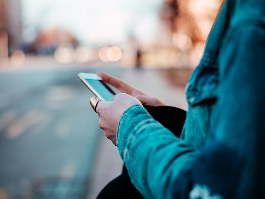 Smartphone an Straßenrand Person guckt auf ihrem Handy auf der Straße