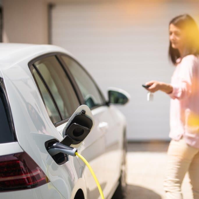 Frau lädt E-Auto Zuhause auf 