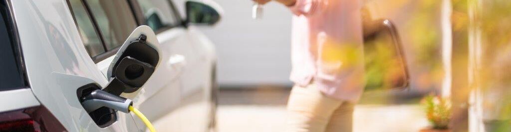 Frau lädt E-Auto Zuhause auf 