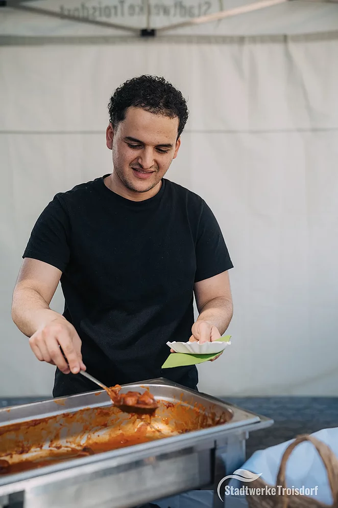 Junger Mann holt Currywurst aus Behälter