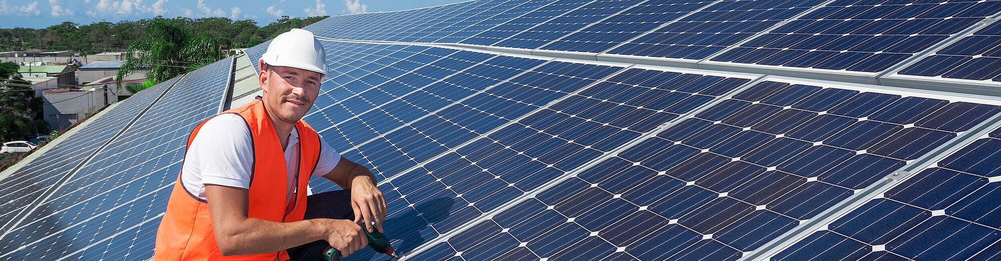 Mann sitzt auf einem Dach mit Solaranlagen 