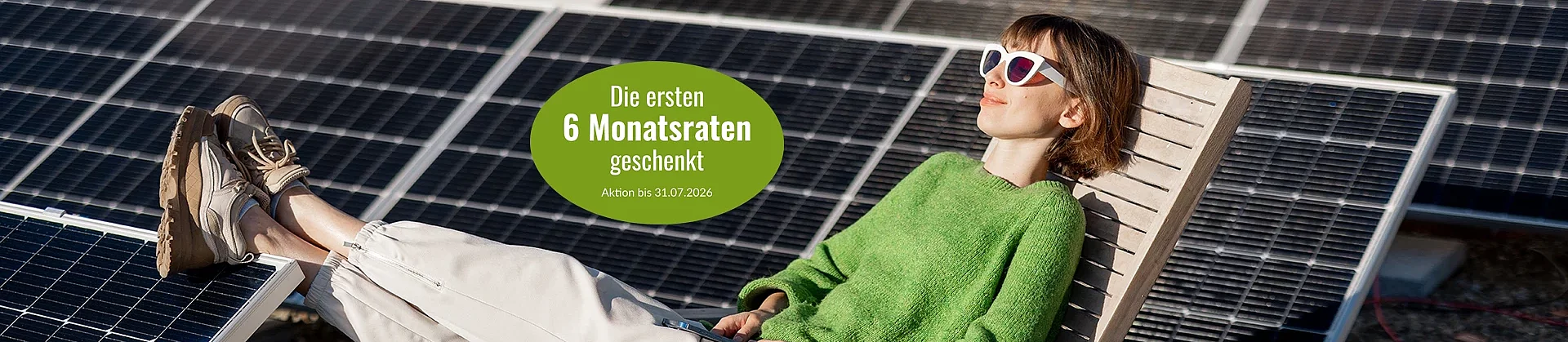 Eine Frau liegt mit Sonnenbrilel in einem Liegestuhl und hat die Füße auf Solarmodule gelegt, die auf dem Flachdach neben ihr aufgebaut sind