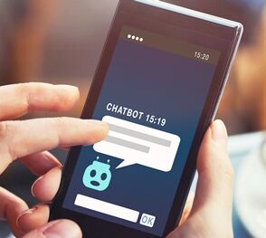 Smartphone in dem ein Chatbot erscheint mit Kaffee 