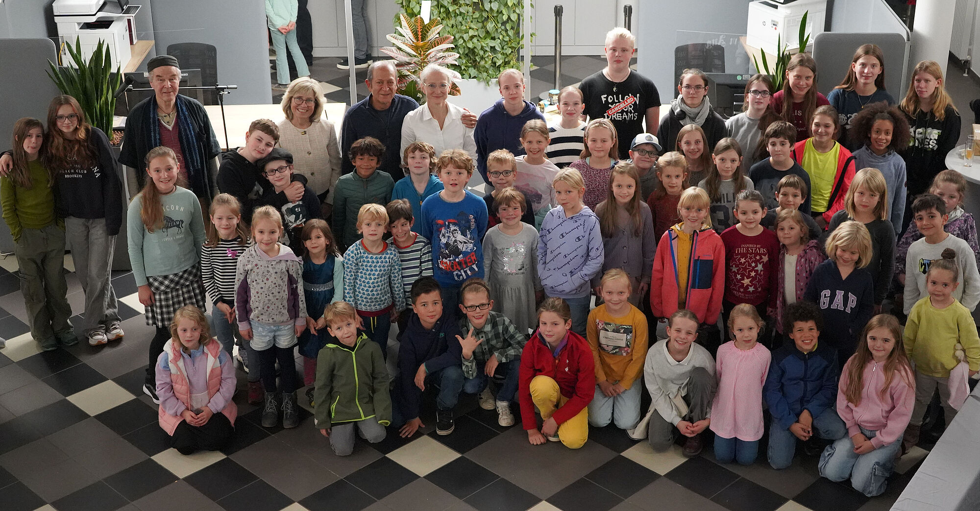 Gruppenbild Finissage Sommerkunstschule 2024 in der Stadtwerke-Galerie Gruppenbild von zahlreichen Kindern und Jugendlichen der Sommerkunstschule 2024 gemeinsam mit der Schauspieler und professionelle Geschichtenerzähler Peter Glass, Stadtwerke-Geschäftsführerin Andrea Vogt sowie Masoud Sadedin und Jette Jertz von der Troisdorfer KreativWerkstatt im Kundenzentrum des Lokalversorgers. ünst-lern der diesjährigen Sommerkunstschule, um gemeinsam das Finale der Ausstellung „Glück hat viele Farben“ in der Stadtwerke-Galerie zu feiern.