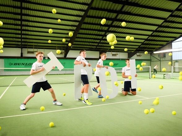 Kinder spielen Tennis Tennisspieler mit Schriftzug Troi auf Tennisplatz