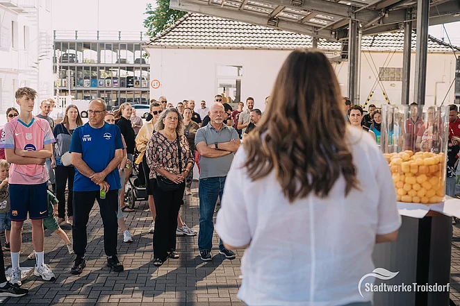 Stadtwerkemitarbeiterin steht auf Podium vor viele Menschen