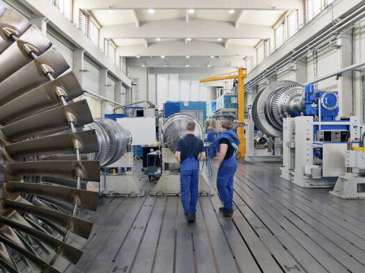 Zwei Männer im Blaumann stehen in einer Industrie und Produktionshalle