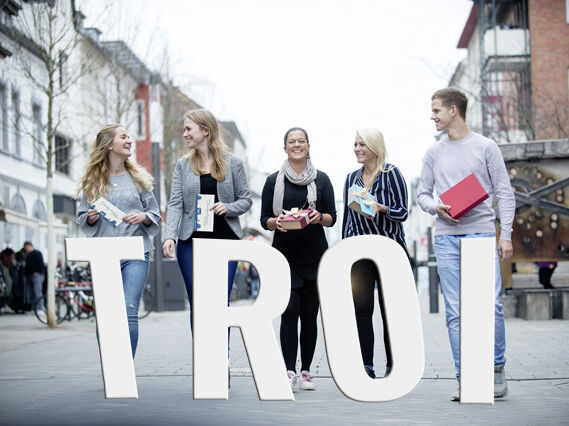 Menschen mit Stadtgutschein und Schriftzug Troi in der Troisdorfer Innenstadt