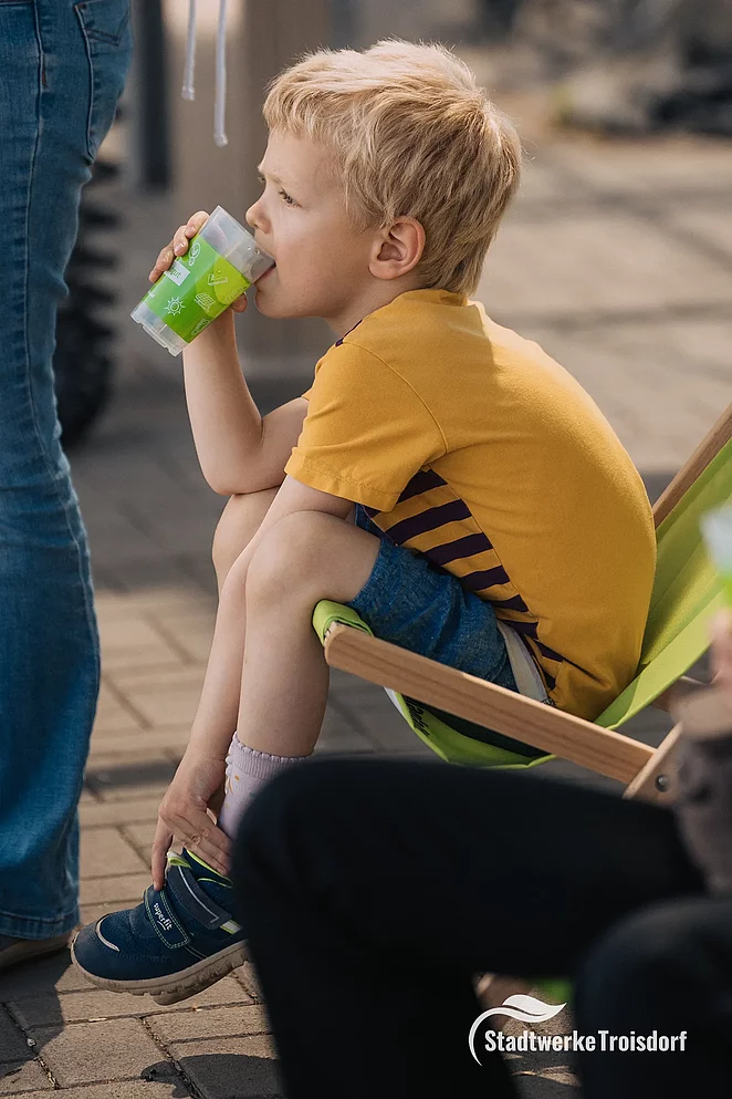 Kind trinkt Wasser im Liegestuhl