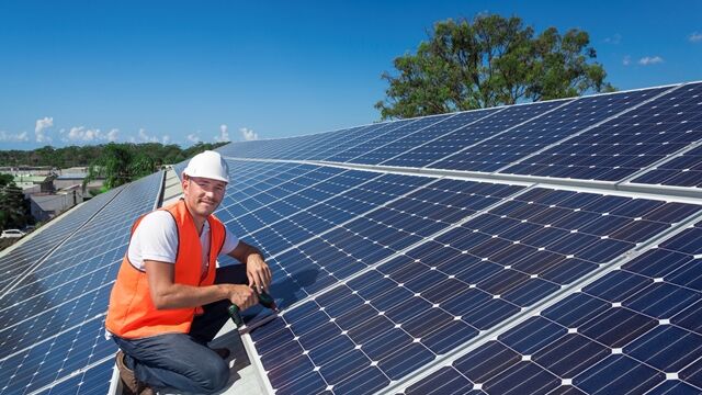 Solarpanelen werden auf Dach montiert Mann sitzt auf einem Dach mit Solaranlagen