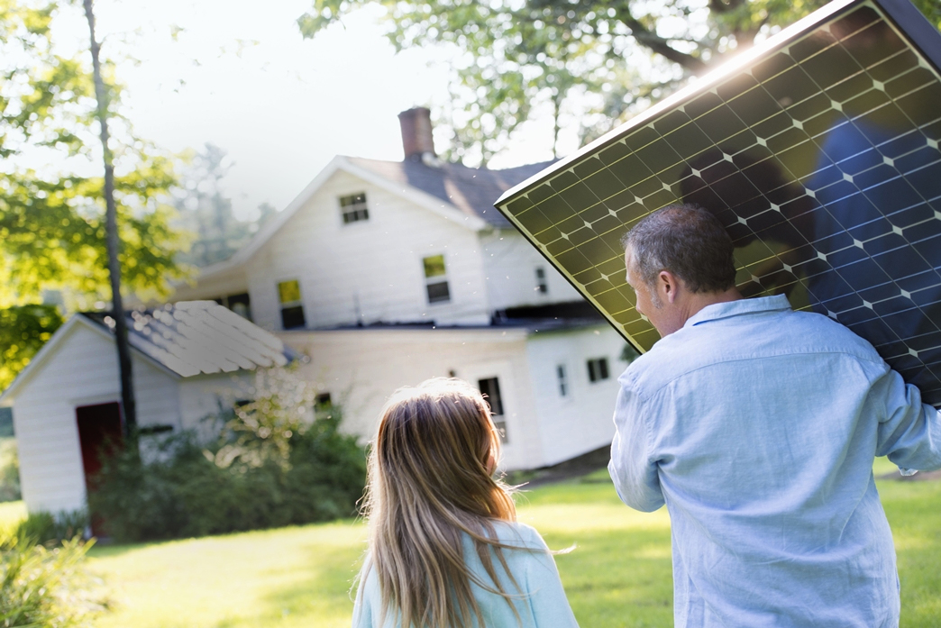 Ein Mädchen steht nehmen einem Mann der Solarpanele zum Haus trägt