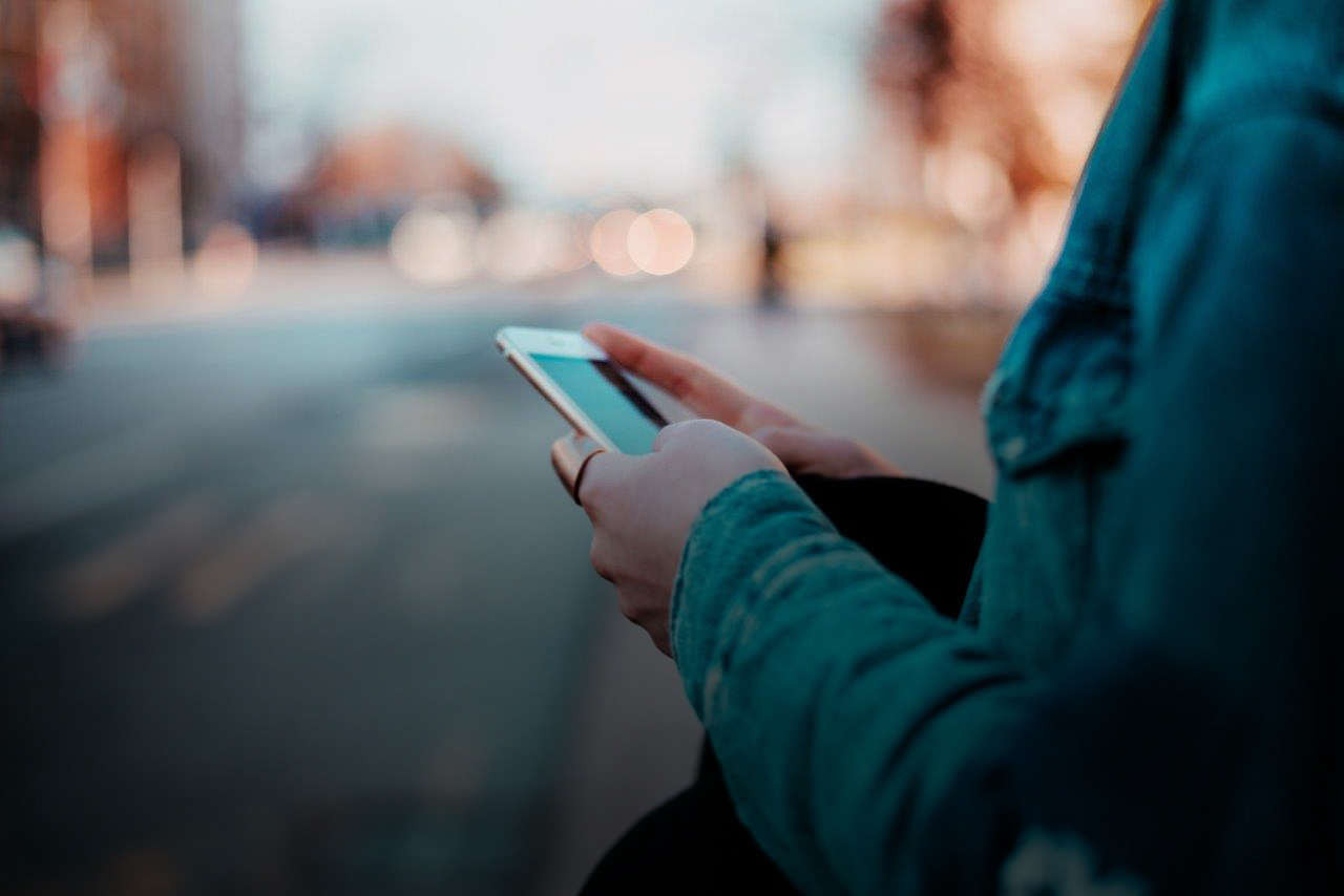 Frau hat ein Handy in der Hand und tippt auf diesem