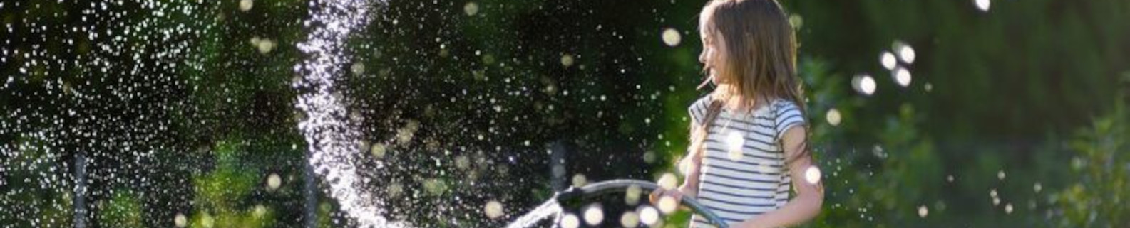 Mädchen spielt mit einem Wasserschlauch 