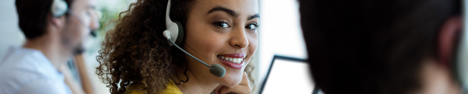 Servicemitarbeiter sitzend vor einem Computer mit einem Headset 