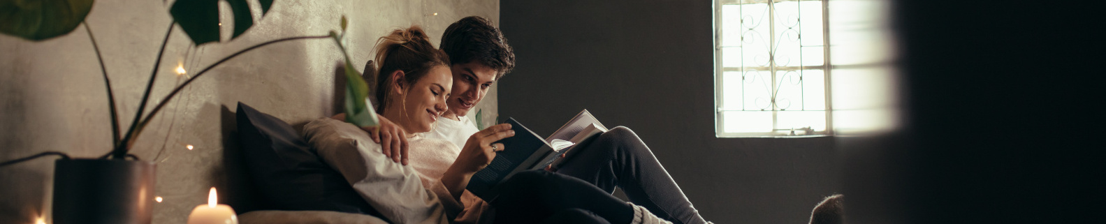 Paar liegt gemütlich beisammen und liest ein Buch 