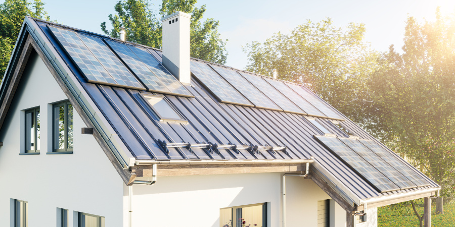 Haus mit Solaranlagen auf dem Dach Haus mit Solaranlagen auf dem Dach umgeben von einer grünen Landschaft