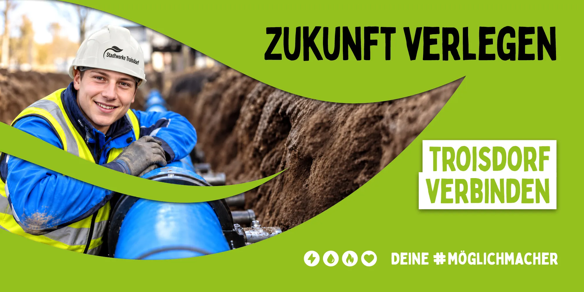 Ein junger Mann mit Schutzhelm sitzt in einer Baugrube und stützt sich lächelnd auf einem Rohr ab