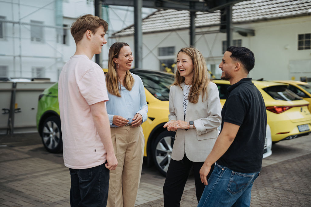 vier Mitarbeitende stehen auf dem Betriebshof zusammen und unterhalten sich