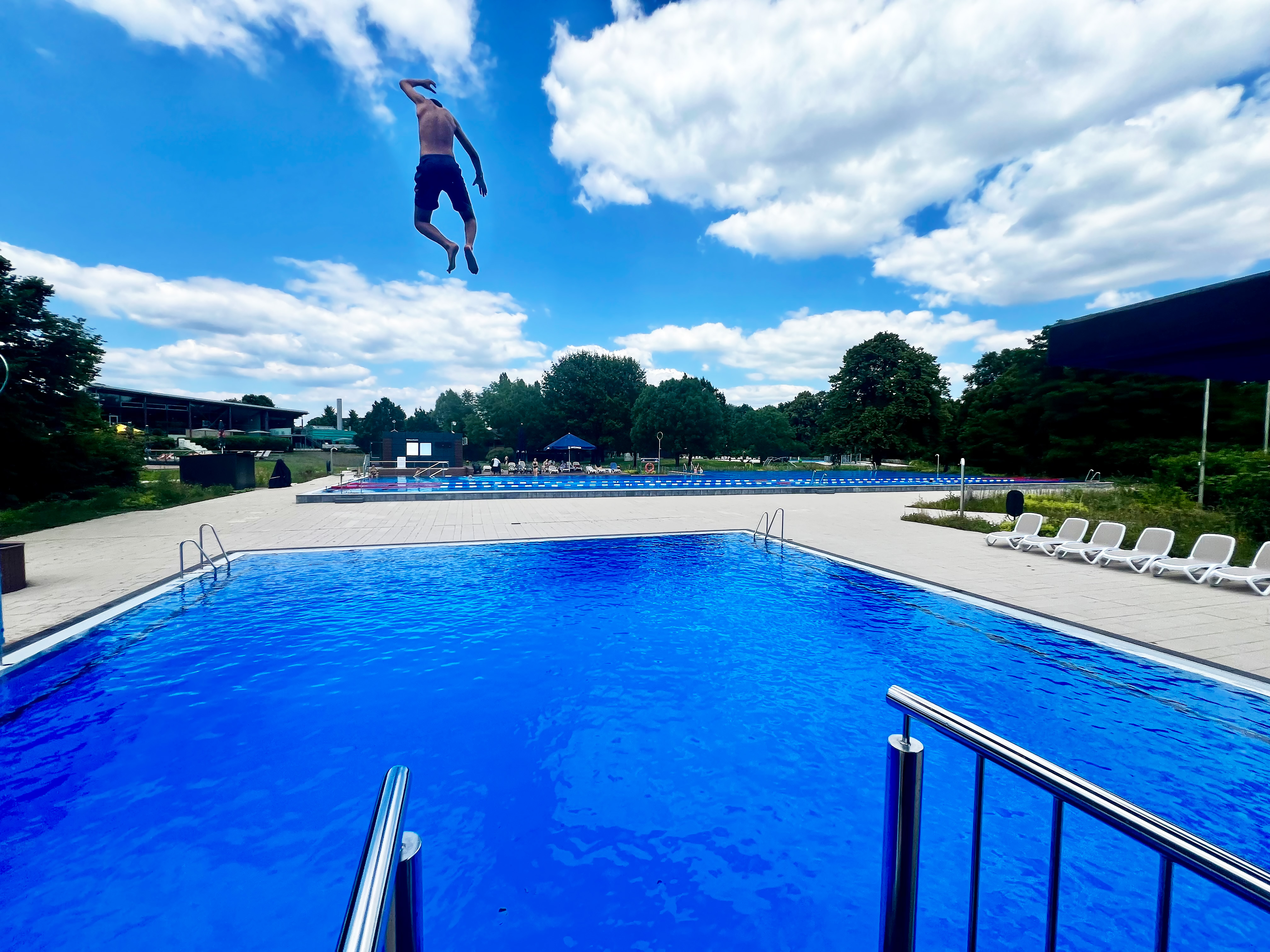 Mann springt vor der AGGUA-Freibad-Kulisse ins Becken