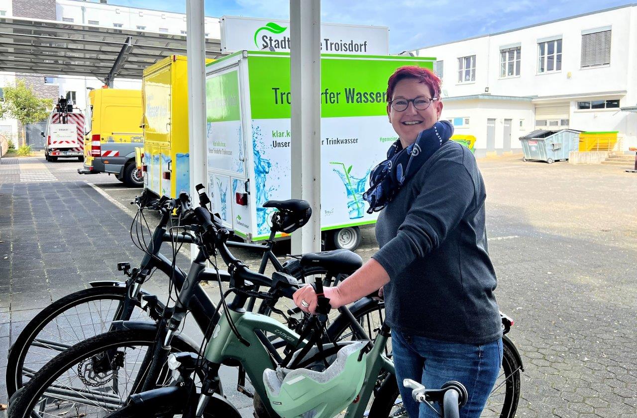 Stadtradeln 2024 Mitarbeiterin steht auf dem Betriebshof an ihrem Fahrrad und schaut in die Kamera