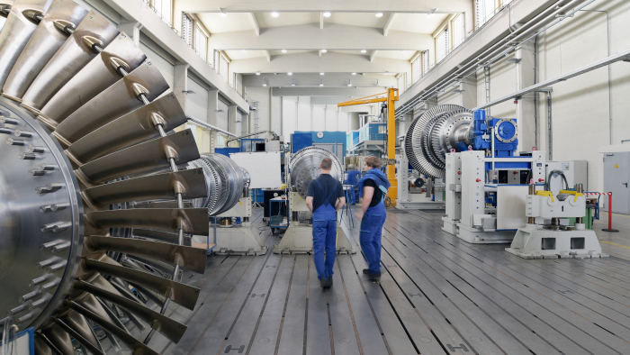 Zwei Männer im Blaumann stehen in einer Industrie und Produktionshalle